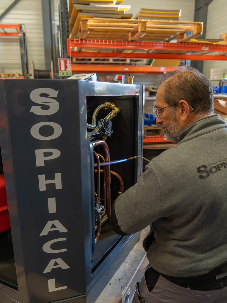 Technicien Sophiacal en assemblage d’une pompe à chaleur dans l’atelier en Isère